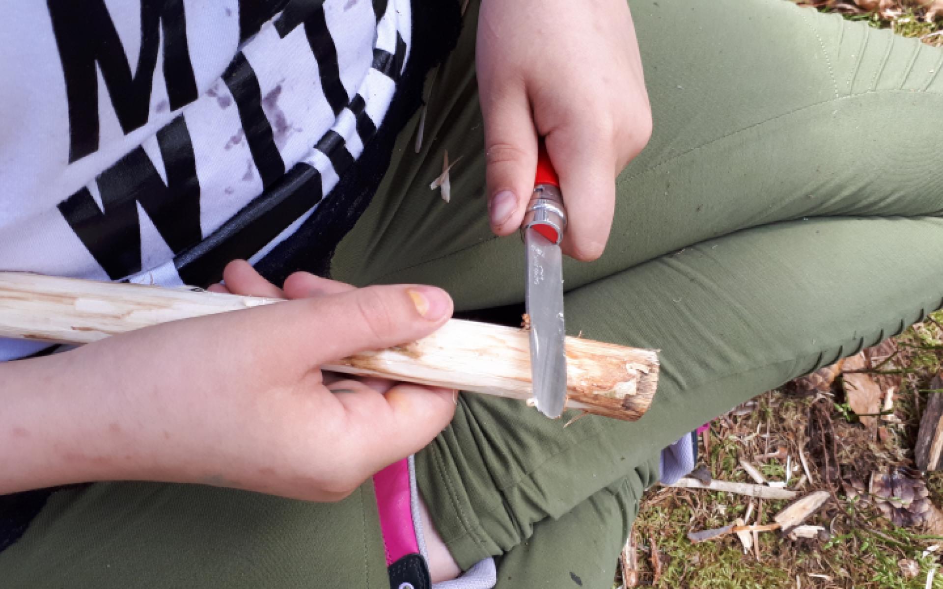 Bub mit Taschenmesser beim Schnitzen
